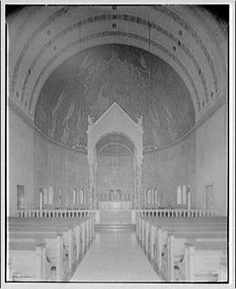 Black and white long-shot photograph of the interior of a church, facing the altar with a view of the pews as well as the high arched ceilings.